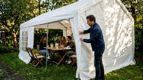 Iemand maakt de zijwand van de partytent in de tuin dicht.
